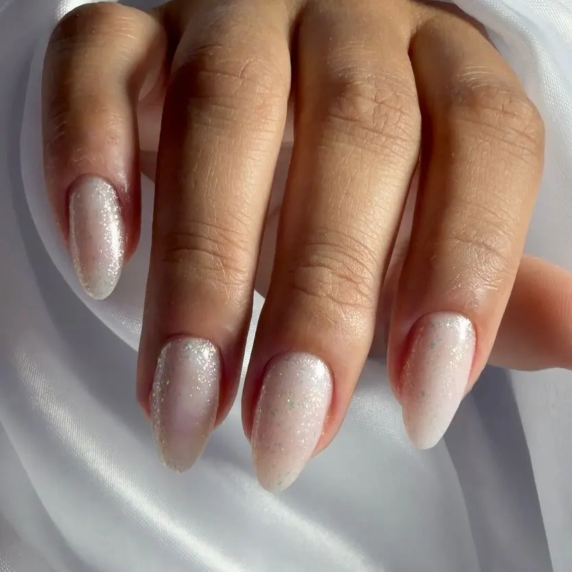 Mão com unhas amendoadas em nude perolado com brilho fino